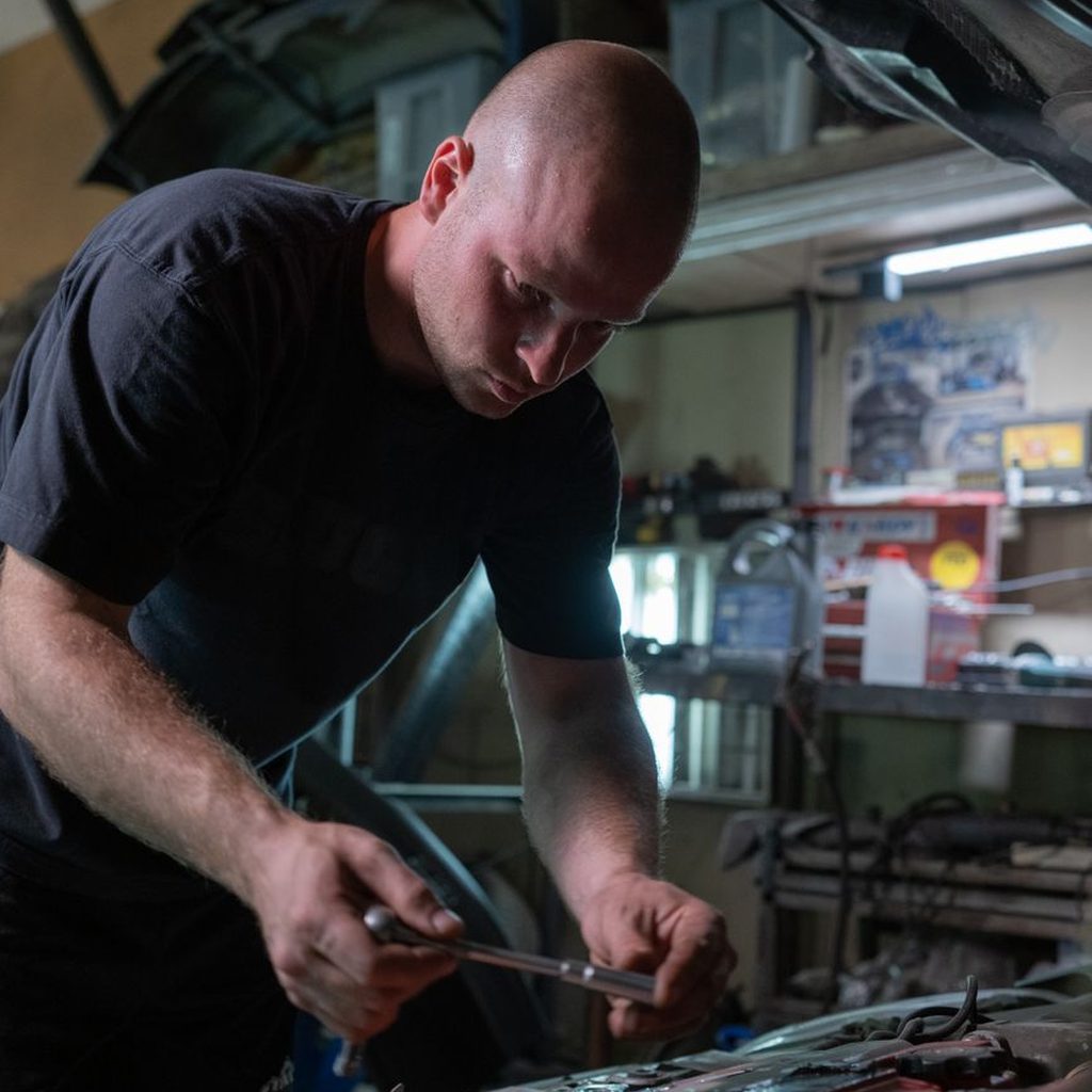 Mechanic working with a wrench under the hood of a car